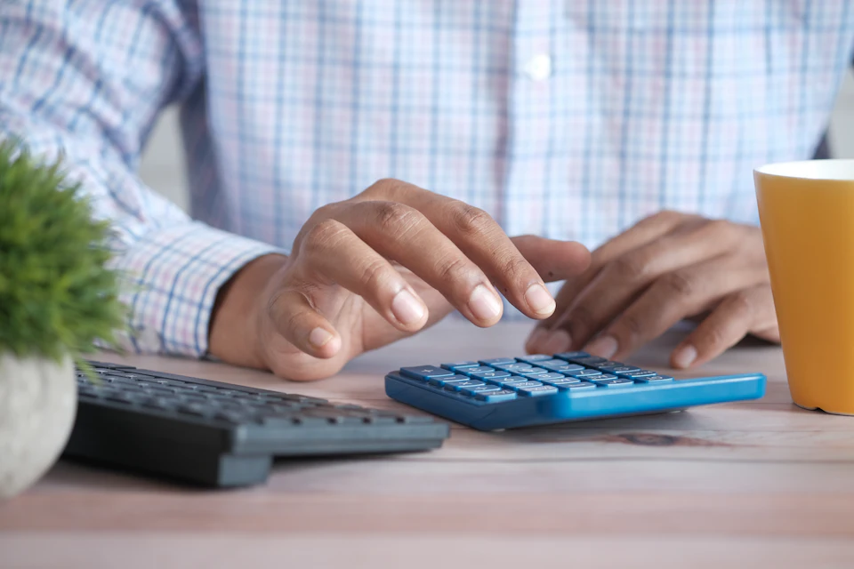 Manos con una calculadora y facturas sobre la mesa